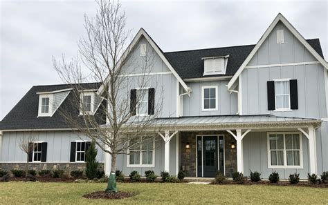 light grey house with black metal roof|grey house with black awnings.